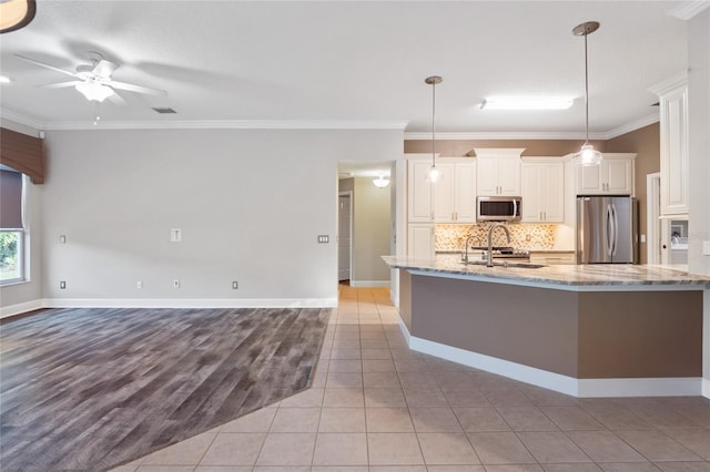 kitchen featuring light stone counters, ceiling fan, ornamental molding, appliances with stainless steel finishes, and tasteful backsplash