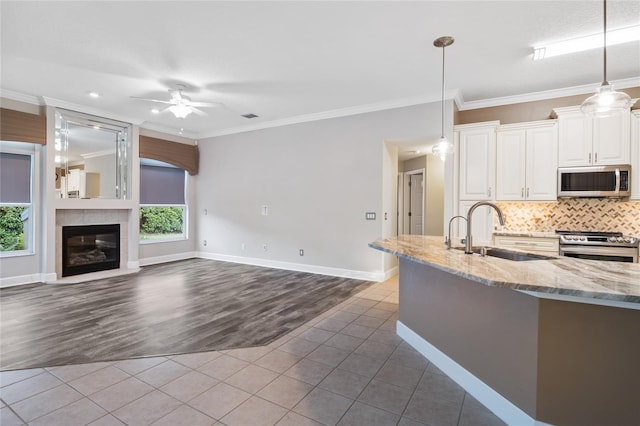 kitchen with a sink, backsplash, ornamental molding, stainless steel appliances, and dark tile patterned flooring