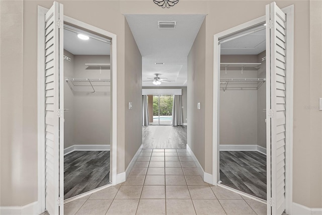 corridor featuring light tile patterned flooring, baseboards, and visible vents