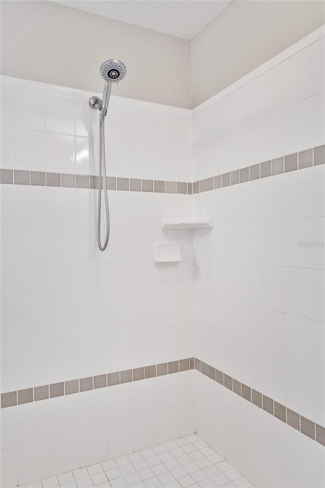 bathroom with a tile shower and a textured ceiling