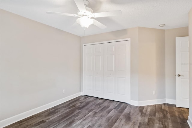 unfurnished bedroom featuring a ceiling fan, baseboards, dark wood-style flooring, and a closet