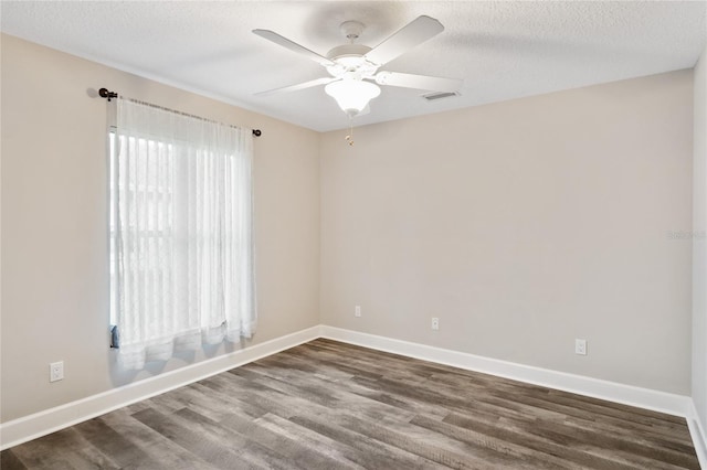 unfurnished room with dark wood finished floors, baseboards, visible vents, and a textured ceiling