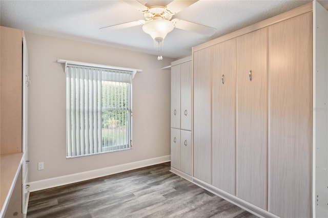 unfurnished bedroom with wood finished floors, baseboards, and ceiling fan