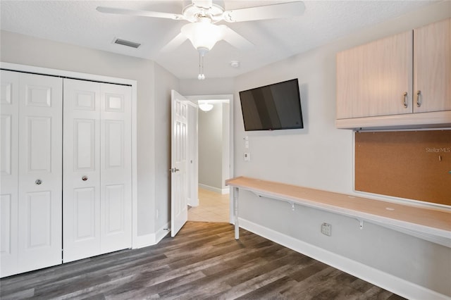 unfurnished bedroom featuring visible vents, baseboards, dark wood finished floors, a closet, and a ceiling fan