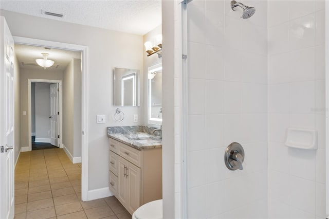 full bathroom featuring visible vents, a textured ceiling, vanity, and a tile shower