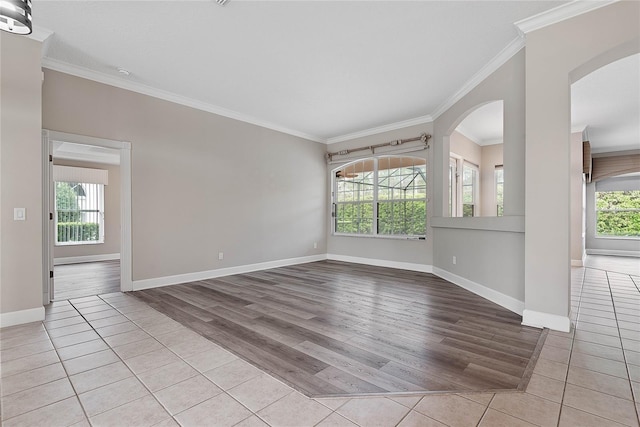 spare room featuring baseboards, plenty of natural light, light wood-style floors, and ornamental molding