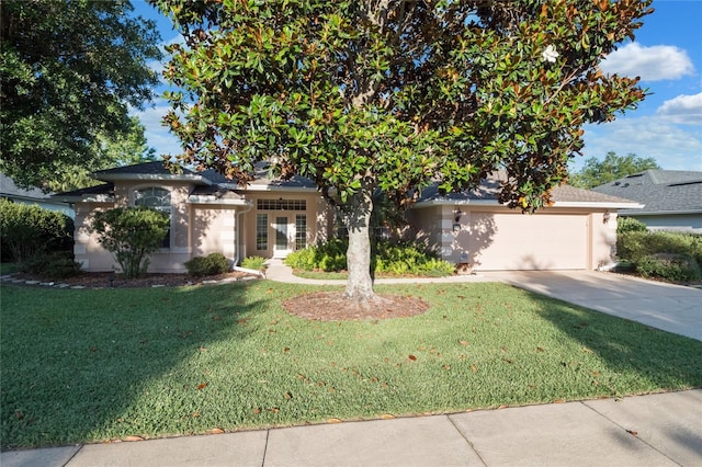 obstructed view of property with a garage, driveway, a front yard, and stucco siding