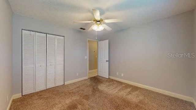 unfurnished bedroom featuring baseboards, ceiling fan, carpet, a textured ceiling, and a closet