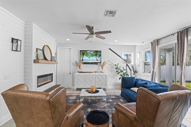562 Kendall Crossing Dr, Saint Johns, FL 32259 - living area featuring ceiling fan, a textured ceiling, a glass covered fireplace, visible vents, and stairway