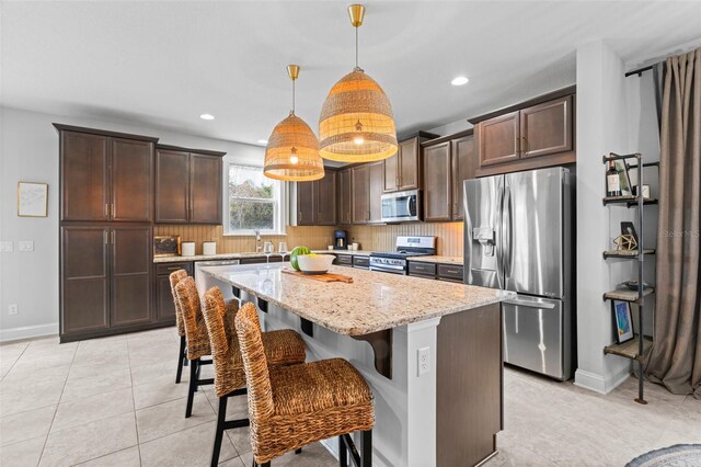 562 Kendall Crossing Dr, Saint Johns, FL 32259 - kitchen with tasteful backsplash, light stone counters, dark brown cabinetry, and stainless steel appliances
