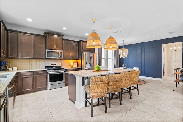 562 Kendall Crossing Dr, Saint Johns, FL 32259 - kitchen with light tile patterned flooring, appliances with stainless steel finishes, an inviting chandelier, and a kitchen breakfast bar