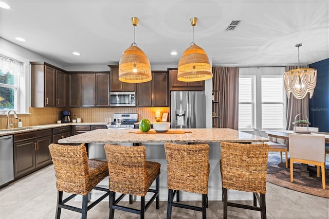 562 Kendall Crossing Dr, Saint Johns, FL 32259 - kitchen with dark brown cabinets, visible vents, a sink, stainless steel appliances, and a notable chandelier