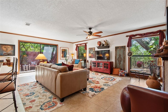 living room with light tile patterned flooring, visible vents, a ceiling fan, and ornamental molding