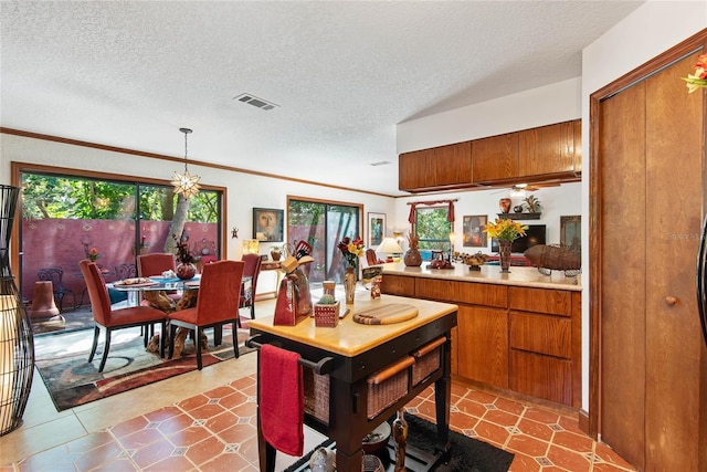 kitchen featuring brown cabinetry, visible vents, a textured ceiling, and light countertops