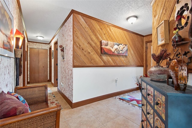 hallway featuring light tile patterned floors, wallpapered walls, a textured ceiling, and crown molding