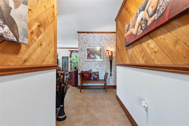 hallway with tile patterned flooring, a textured ceiling, and baseboards