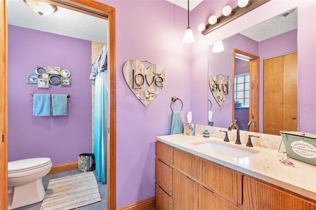 bathroom featuring baseboards, toilet, vanity, and a textured ceiling