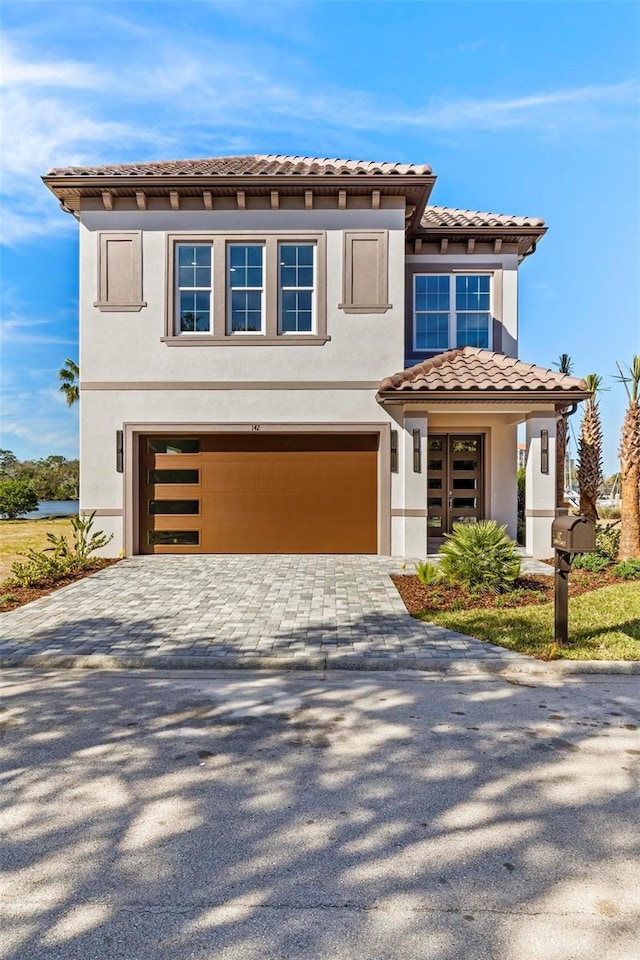 view of front of home with a garage, a tiled roof, decorative driveway, and stucco siding