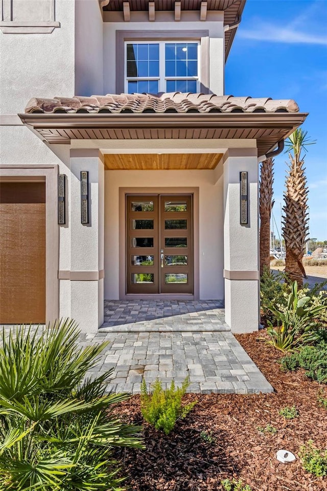 doorway to property with a tiled roof and stucco siding