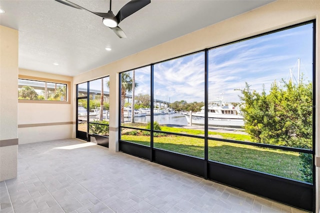 unfurnished sunroom featuring a water view and ceiling fan