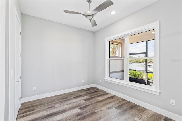 spare room with wood finished floors, a ceiling fan, and baseboards