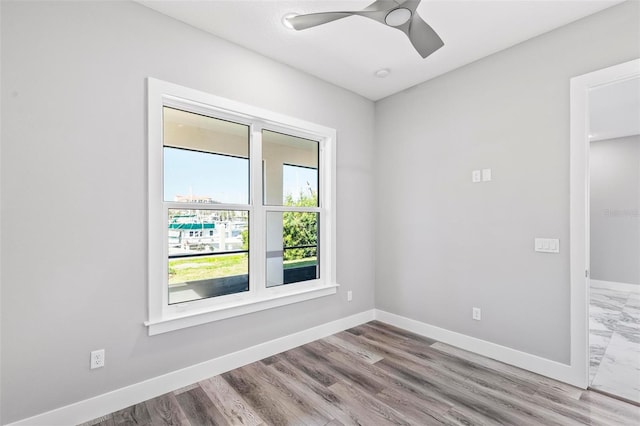 empty room with baseboards, a ceiling fan, and wood finished floors