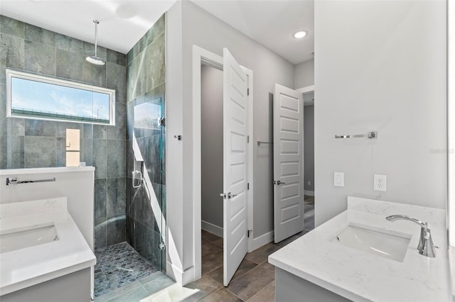 bathroom with a sink, a shower stall, baseboards, and double vanity