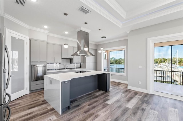 kitchen featuring island exhaust hood, light countertops, visible vents, decorative backsplash, and an island with sink