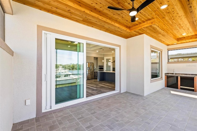 exterior space featuring a tray ceiling, wooden ceiling, and a ceiling fan