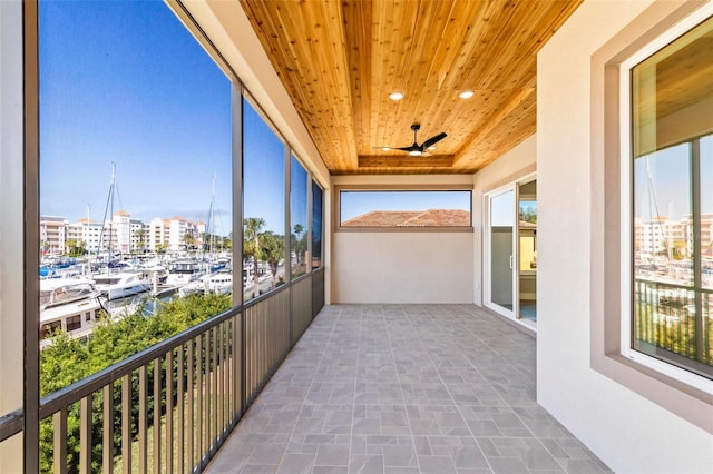 unfurnished sunroom with a view of city, a tray ceiling, wooden ceiling, and a ceiling fan