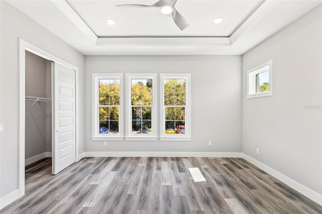 unfurnished bedroom featuring a raised ceiling, baseboards, and wood finished floors