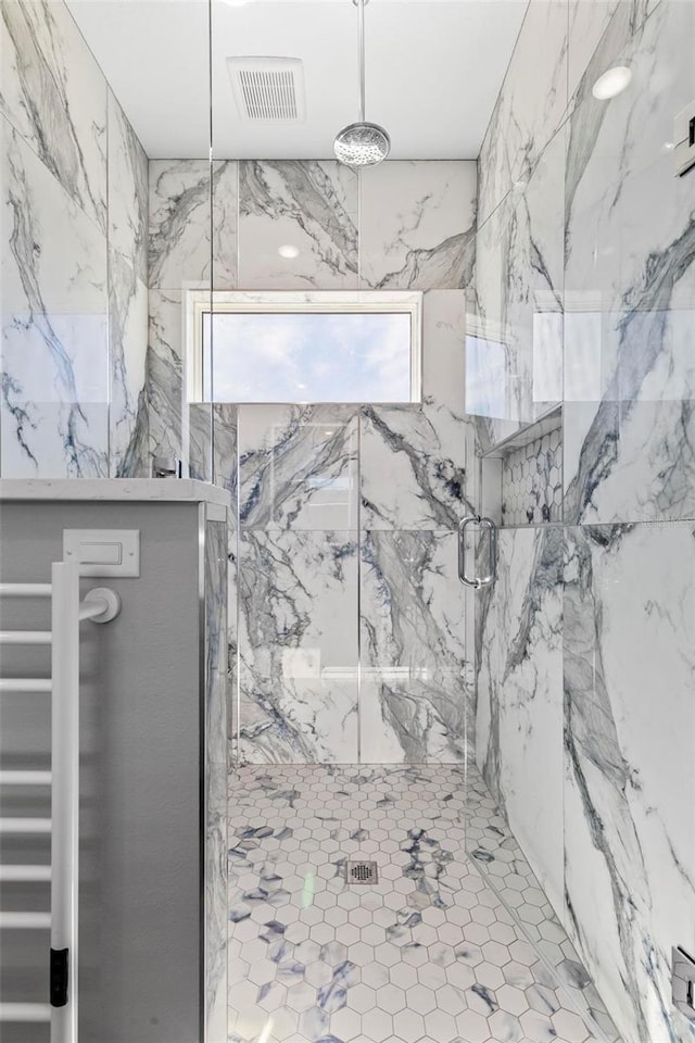 full bathroom with a marble finish shower and visible vents