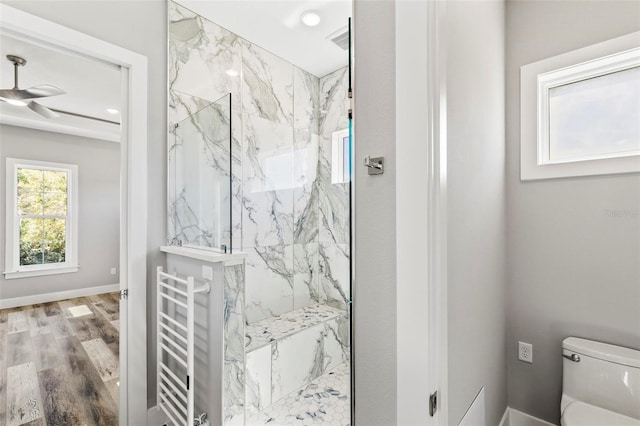 bathroom featuring toilet, a marble finish shower, baseboards, and wood finished floors