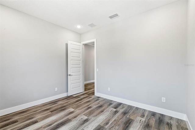 spare room with visible vents, baseboards, and wood finished floors