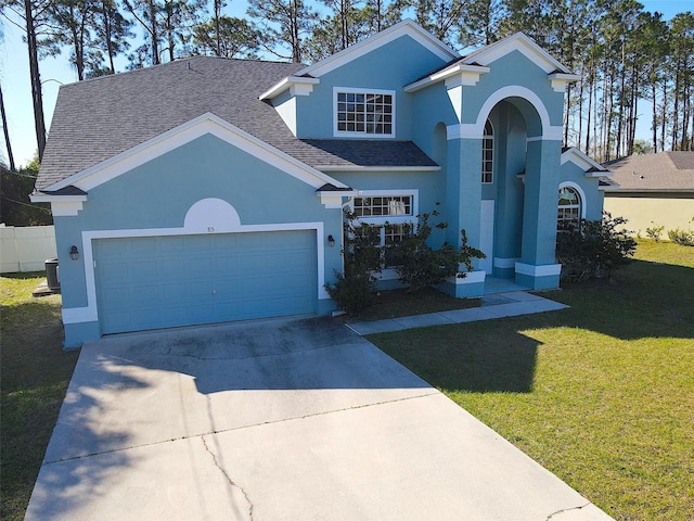 traditional home with a front lawn, concrete driveway, roof with shingles, stucco siding, and an attached garage