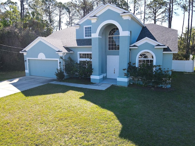 traditional-style home with a shingled roof, a front lawn, an attached garage, and stucco siding