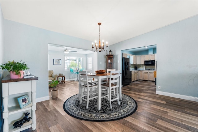 dining space featuring ceiling fan with notable chandelier, dark wood-type flooring, and baseboards