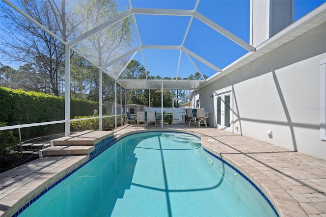 view of swimming pool with glass enclosure, a fenced in pool, a fenced backyard, french doors, and a patio area