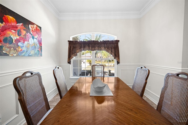 dining space with a wainscoted wall, ornamental molding, and a decorative wall