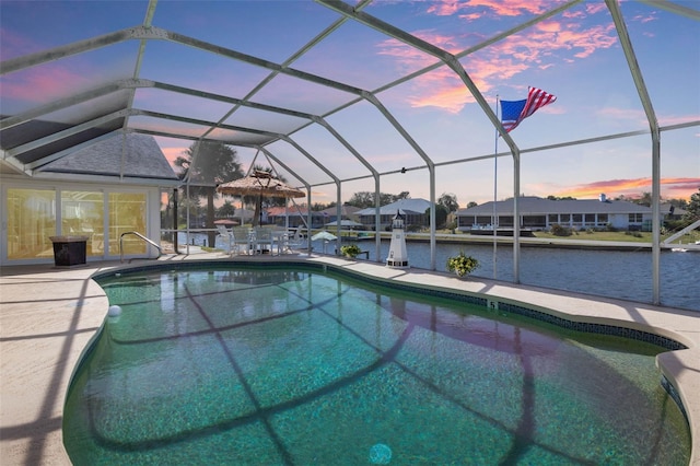 pool at dusk with a patio, a water view, a lanai, and an outdoor pool