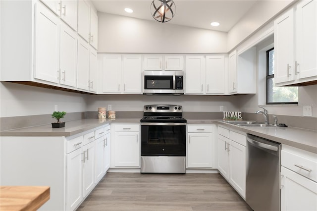 kitchen with light wood-style flooring, stainless steel appliances, a sink, white cabinetry, and light countertops