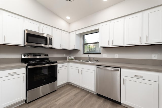 kitchen with white cabinets, stainless steel appliances, light wood-type flooring, a sink, and recessed lighting