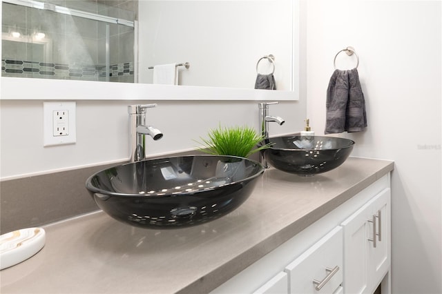 bathroom with a tile shower, double vanity, and a sink