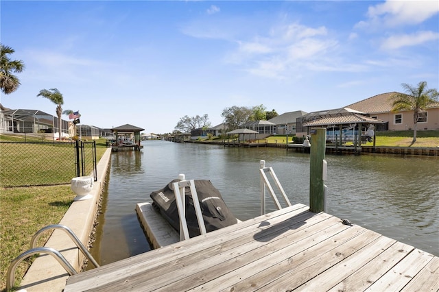 dock area featuring a water view, a residential view, fence, and a lawn