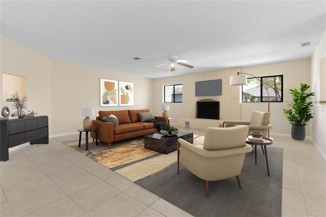 living area featuring light tile patterned floors, ceiling fan, a fireplace, visible vents, and baseboards