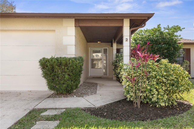 view of exterior entry featuring a garage and stucco siding