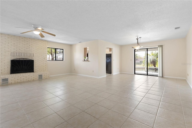 unfurnished living room featuring light tile patterned floors, a textured ceiling, a fireplace, and visible vents