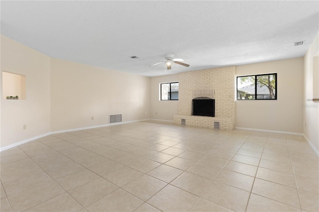 unfurnished living room with plenty of natural light, a brick fireplace, and visible vents