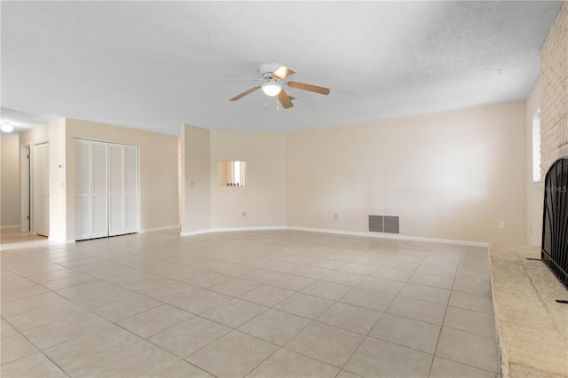 unfurnished living room featuring light tile patterned floors, visible vents, a brick fireplace, ceiling fan, and a textured ceiling