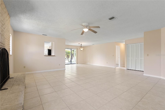 unfurnished living room with a fireplace, light tile patterned floors, visible vents, a ceiling fan, and a textured ceiling